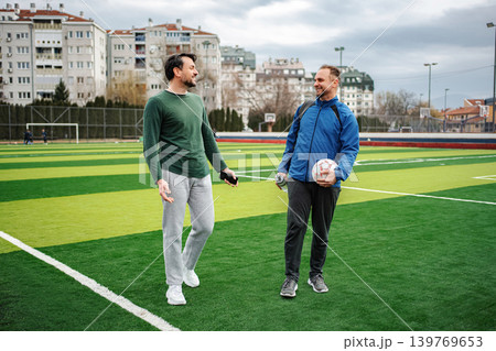 Two adult men talking on a soccer field 139769653