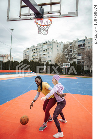 Diverse women friends playing basketball on outdoor court Diverse women friends playing basketball on outdoor court 139769674