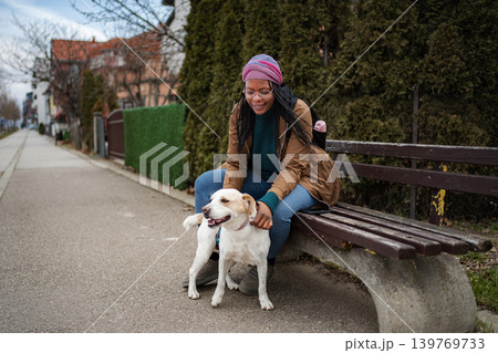 Woman petting happy dog sitting on park bench outdoors Woman petting happy dog sitting on park bench outdoors 139769733