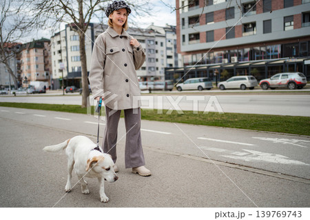 Young woman walking pet dog on urban street 139769743