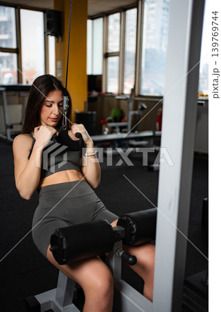 Young woman training back muscles with lat pulldown machine 139769744