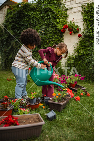 Children watering flowers in backyard garden together Children watering flowers in backyard garden together 139769981