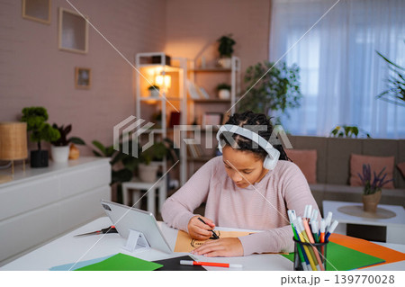 Young girl drawing at home with headphones and tablet Young girl drawing at home with headphones and tablet 139770028