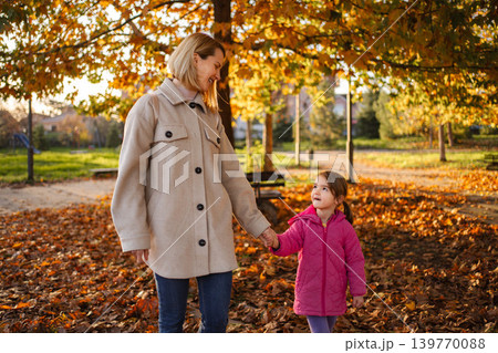 Mother and daughter enjoying walk in autumn park Mother and daughter enjoying walk in autumn park 139770088
