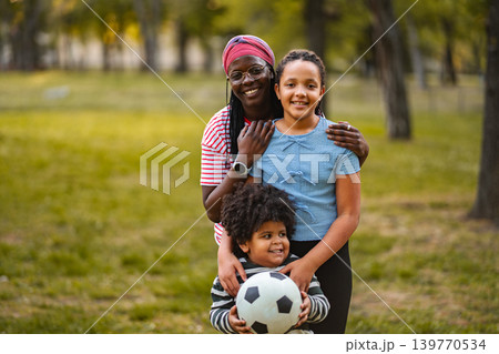 African American mother and happy children playing soccer outdoors African American mother and happy children playing soccer outdoors 139770534