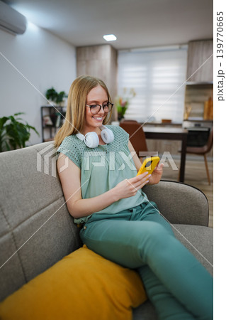 Enjoying a cozy moment with a smartphone and headphones at home Enjoying a cozy moment with a smartphone and headphones at home 139770665