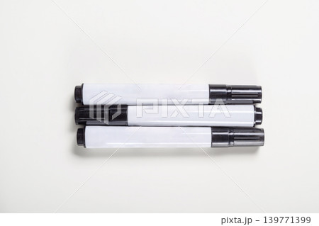 High-angle view of three black permanent markers with white barrels placed parallel to each other on a neutral white surface. Ideal for stationery and office equipment concepts High-angle view of three black permanent markers with white barrels placed parallel to each other on a neutral white surface. Ideal for stationery and office equipment concepts 139771399