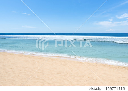 A beautiful and peaceful tropical beach featuring crystal clear turquoise ocean water, white sand, and a bright blue sky on a sunny day 139771516