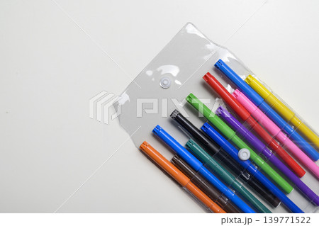 A top-down view of a variety of brightly colored felt-tip pens neatly arranged in a transparent plastic carrying case, set against a clean white background 139771522
