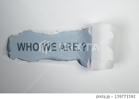 A creative concept image showing the phrase 'WHO WE ARE.?' revealed beneath a strip of torn white paper on a light blue background, representing identity and discovery 139771592