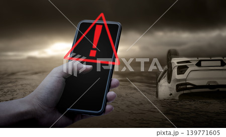 Hand holding a smartphone with a red warning symbol over a flipped car wreckage background. Concept of roadside assistance, emergency alerts, and car insurance claims 139771605