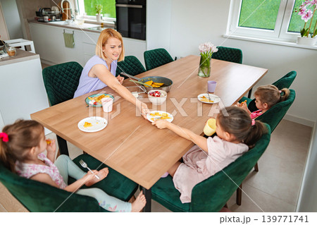Family enjoying breakfast together in a cozy kitchen Family enjoying breakfast together in a cozy kitchen 139771741