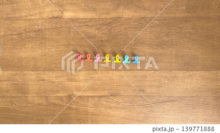木目背景に並ぶ7個の小さなカラフルなクリップ 木目背景に並ぶ7個の小さなカラフルなクリップ 139771888