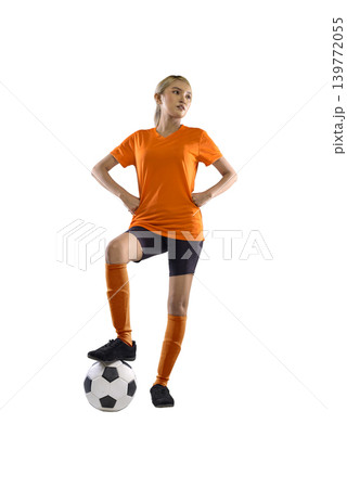 Confident young Indonesian southeast asian female soccer player in an orange jersey and black shorts standing with one foot on a soccer ball, isolated on a white background Confident young Indonesian southeast asian female soccer player in an orange jersey and black shorts standing with one foot on a soccer ball, isolated on a white background 139772055