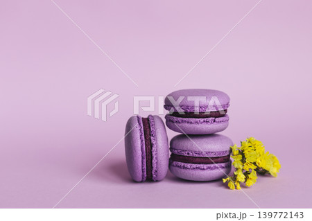Three french macarons with yellow flowers on a purple background. Place for text. 139772143