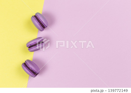 Three french macarons on a yellow and purple background. Place for text. 139772149