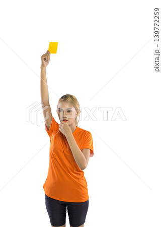 A serious Indonesian southeast asian female sports official in an orange shirt holds up a yellow card and blows a whistle to signal a foul, isolated on a white background A serious Indonesian southeast asian female sports official in an orange shirt holds up a yellow card and blows a whistle to signal a foul, isolated on a white background 139772259