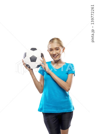 A beautiful young Indonesian southeast asian woman with blonde hair, wearing a blue t-shirt, poses while holding a classic black and white soccer ball near her face against a plain white background 139772261