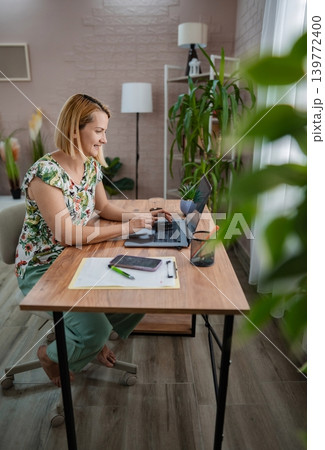 Creative woman working on laptop in a cozy home office 139772400
