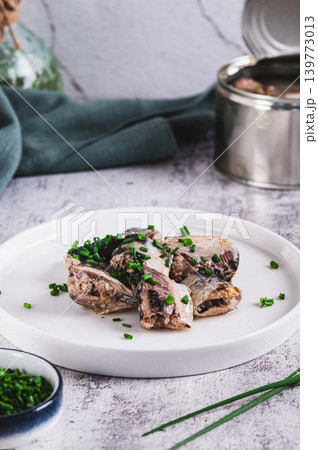 Canned sardines with green onions on a plate on the table vertical view Canned sardines with green onions on a plate on the table vertical view 139773013