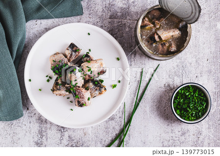 Canned sardines with green onions on a plate on the table top view Canned sardines with green onions on a plate on the table top view 139773015