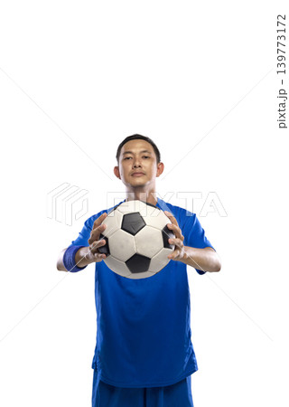 Full length portrait of a confident Indonesian southeast asian male soccer player wearing a blue kit and holding a football, isolated against a white background. Ideal for sports and fitness concepts Full length portrait of a confident Indonesian southeast asian male soccer player wearing a blue kit and holding a football, isolated against a white background. Ideal for sports and fitness concepts 139773172