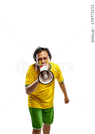 An excited Indonesian southeast asian male soccer fan wearing a yellow and green jersey shouting into a megaphone and cheering with his fist raised, isolated on white background An excited Indonesian southeast asian male soccer fan wearing a yellow and green jersey shouting into a megaphone and cheering with his fist raised, isolated on white background 139773252