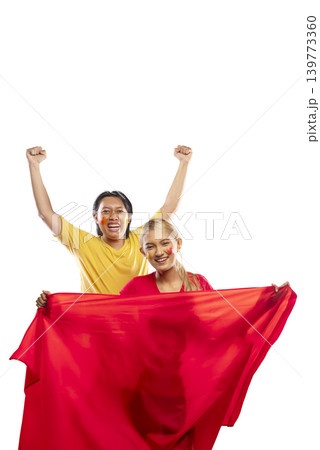 Two young Indonesian southeast asian enthusiastic fans, a man and a woman, cheering for their team with a red flag and face paint, celebrating victory isolated on a white background Two young Indonesian southeast asian enthusiastic fans, a man and a woman, cheering for their team with a red flag and face paint, celebrating victory isolated on a white background 139773360