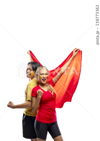 Two young Indonesian southeast asian enthusiastic fans, a man and a woman, cheering for their team with a red flag and face paint, celebrating victory isolated on a white background 139773362