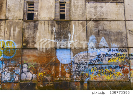 Historic industrial building facade showing signs of decay and colorful street art embellishments 139773596