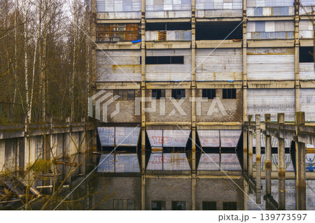 Mirror water decay. Serene water mirrors old industrial site with broken roofs and surrounding trees Mirror water decay. Serene water mirrors old industrial site with broken roofs and surrounding trees 139773597