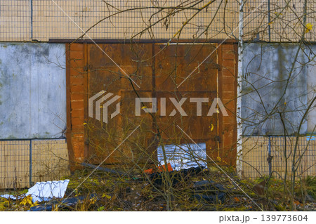 Abandoned rusted wall with broken glass. Weathered metal barrier blanketed by green moss and corrosion Abandoned rusted wall with broken glass. Weathered metal barrier blanketed by green moss and corrosion 139773604