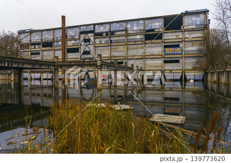 Abandoned industrial scene. Deserted industrial area with broken structures and murky pools of water Abandoned industrial scene. Deserted industrial area with broken structures and murky pools of water 139773620