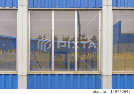 Transparent glass pane encapsulates interior desks and outdoor trees in harmonious display Transparent glass pane encapsulates interior desks and outdoor trees in harmonious display 139773642