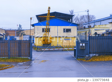 Industrial activity underway with crane and heavy equipment beside yellow structure and fencing Industrial activity underway with crane and heavy equipment beside yellow structure and fencing 139773648