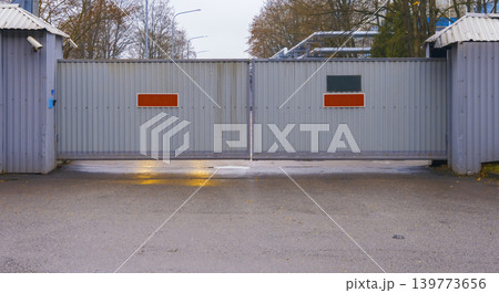 Shielded entry point at night. Locked grille illuminated by amber signals over slick wet pavement Shielded entry point at night. Locked grille illuminated by amber signals over slick wet pavement 139773656