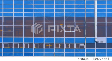 Sleek office tower with reflections. Contemporary structure featuring illuminated windows and grid design 139773661