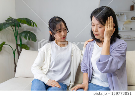 頭をおさえる母と心配する娘 139773851