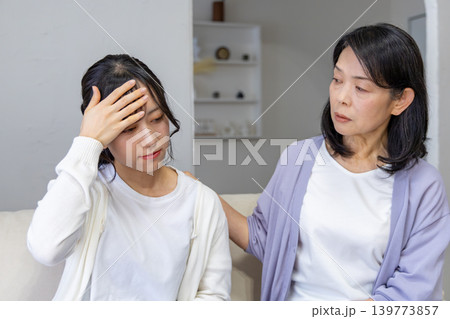 頭をおさえる娘と心配する母親 頭をおさえる娘と心配する母親 139773857