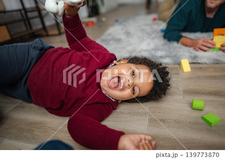 Happy toddler laughing playing with toy on floor Happy toddler laughing playing with toy on floor 139773870