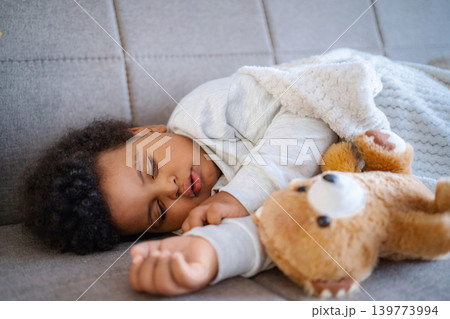 Sleeping african american child napping peacefully with teddy bear 139773994
