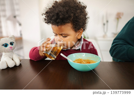 Young child drinking juice enjoying healthy breakfast at home Young child drinking juice enjoying healthy breakfast at home 139773999