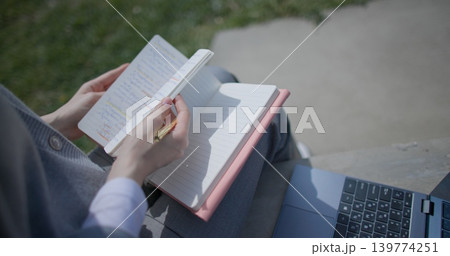 A close-up shot of a hand-held girl holding a pen and leafing through a notebook with handwritten notes. A close-up shot of a hand-held girl holding a pen and leafing through a notebook with handwritten notes. 139774251