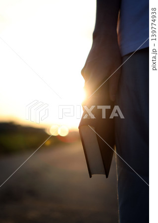 A Christian holding the holy Bible, the word of truth, amidst a landscape of bright sunlight 139774938