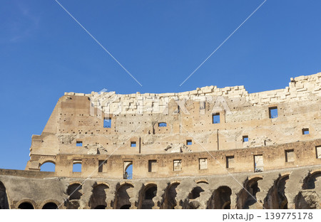 Famous Coliseum in Rome. Colosseum, or Coliseum. Part of the wall of an antique stone structure with arches. Italy, Europe. Famous touristic place in the world, Europe. Beautiful blue sky background. Famous Coliseum in Rome. Colosseum, or Coliseum. Part of the wall of an antique stone structure with arches. Italy, Europe. Famous touristic place in the world, Europe. Beautiful blue sky background. 139775178