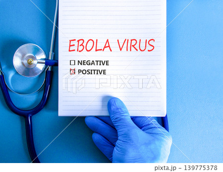 Ebola virus words symbol. Concept word Ebola virus positive on beautiful white note. Beautiful blue background. Doctor hand in blue medical glove. Stethoscope. Medical Ebola virus concept. Copy space 139775378