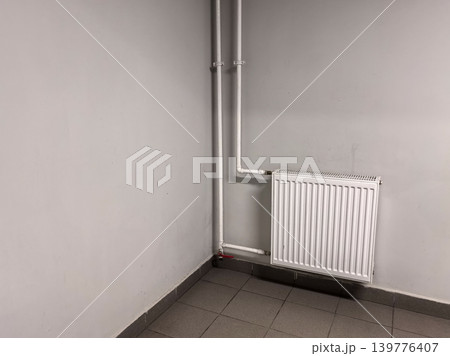 White Heating Radiator on Gray Wall in Corner Location White Heating Radiator on Gray Wall in Corner Location 139776407
