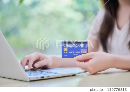 クレジットカードを見ながらパソコン入力する20代の女性 クレジットカードを見ながらパソコン入力する20代の女性 139776818