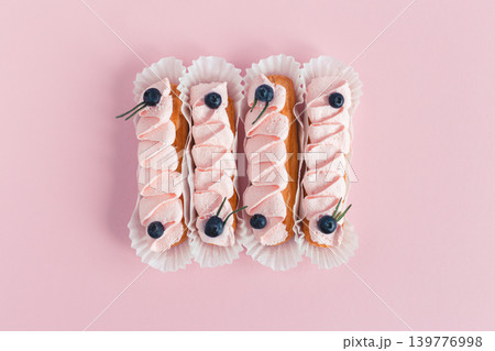 Tasty French eclairs with cream and fresh berries on pink pastel background. Set of delicious eclairs. Tasty French eclairs with cream and fresh berries on pink pastel background. Set of delicious eclairs. 139776998