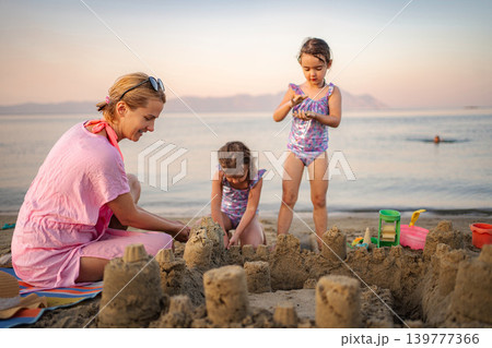 Mother and daughters building sandcastle on Greece beach during summer vacation 139777366